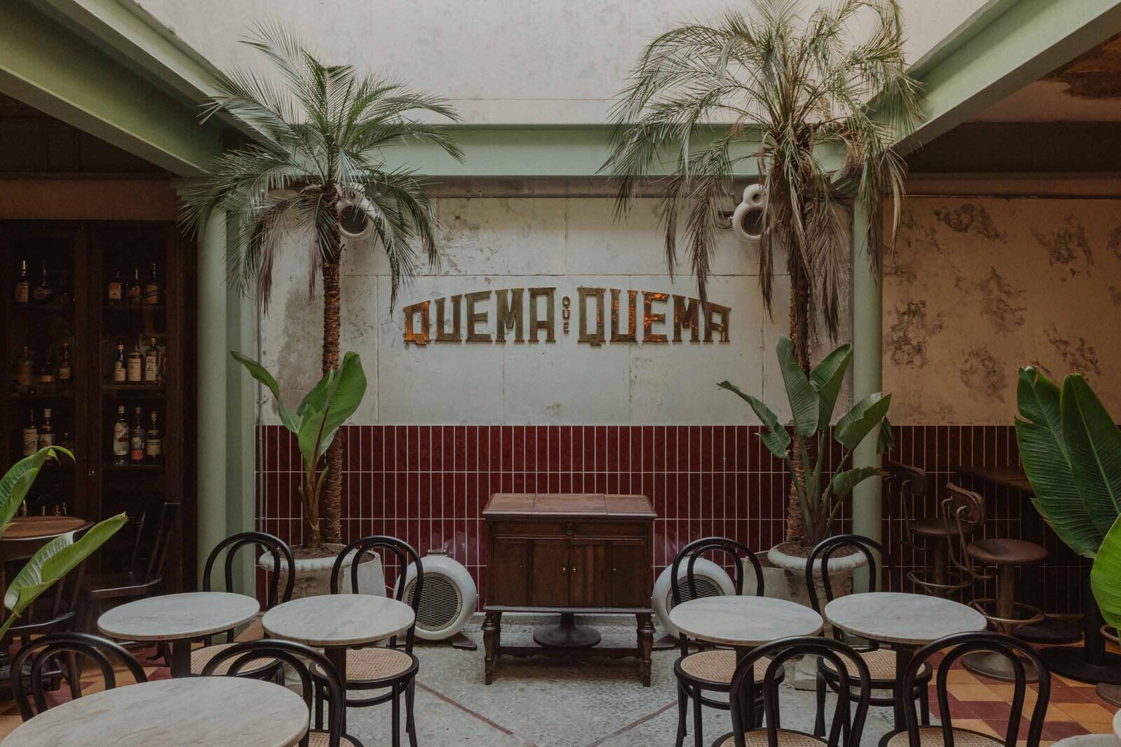 Courtyard of Quema que Quema with palms and wine-red tile