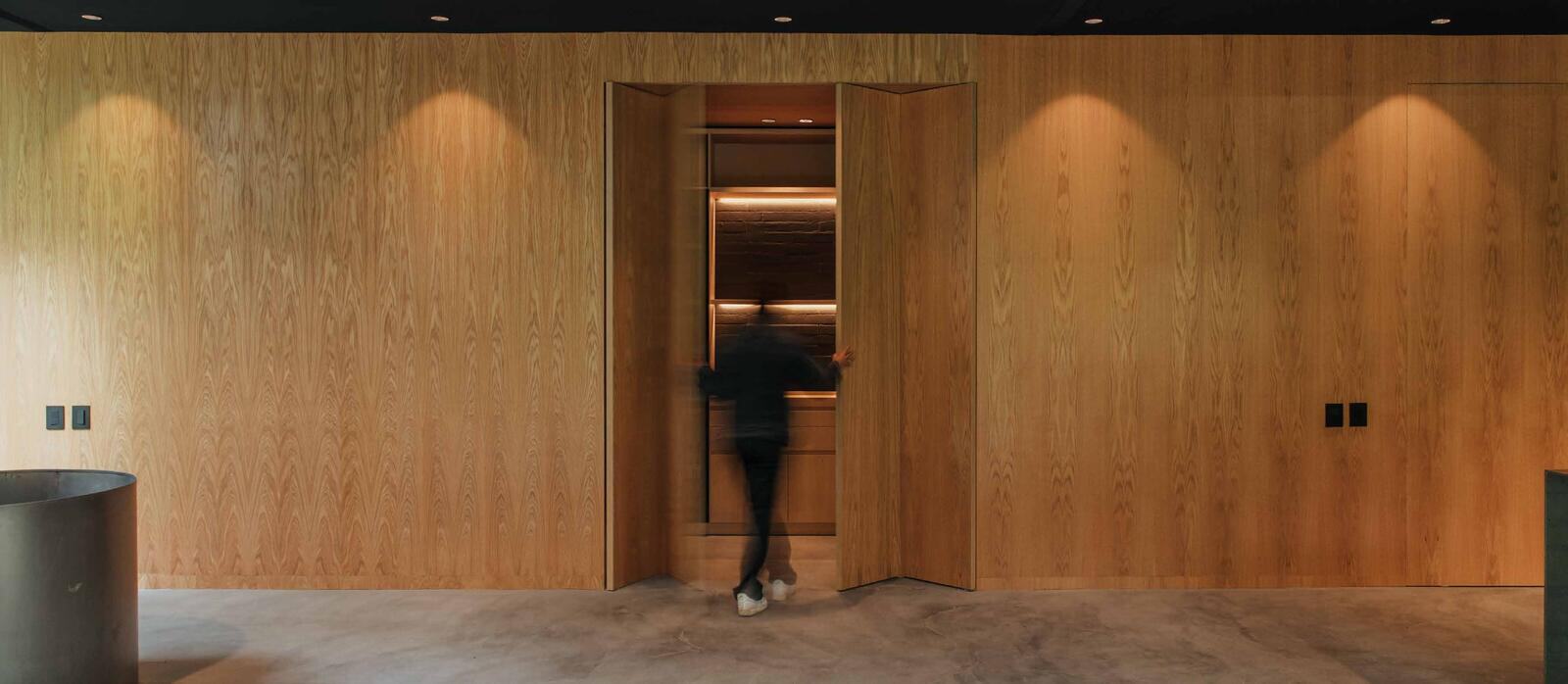 Oak-panelled wall with a pivoting door at Casa S