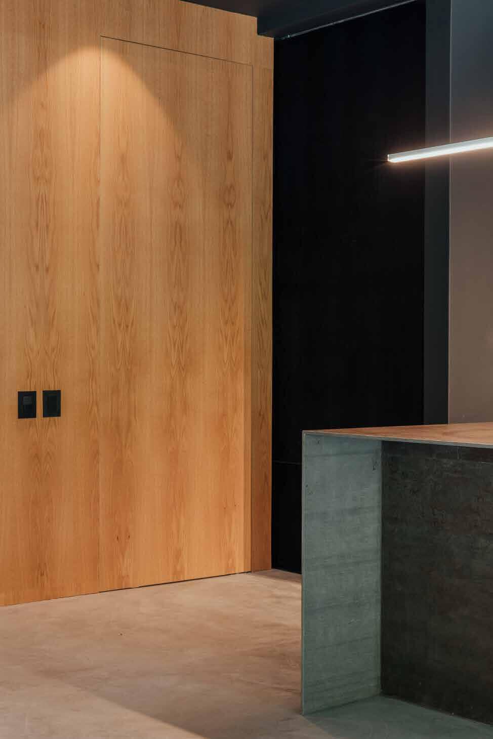 Flush oak door beside a concrete kitchen island at Casa S